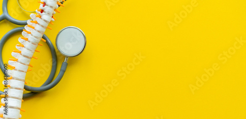 Fotografie close up top view on human skeleton at lower back and stethoscope on yellow back