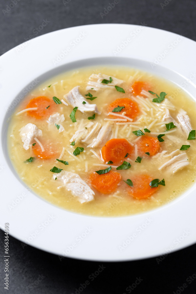 Chicken soup with vegetables on black slate background. Close up Chicken soup with vegetables on black slate background. Close up