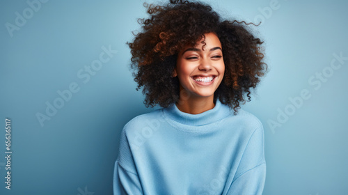 portrait of a strong, independent African American woman against a blue background while wearing a blue sweater