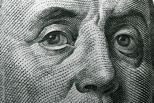 Benjamin Franklin's eyes on a hundred dollar bill. Benjamin Franklin portrait. United States national currency banknote fragment photo