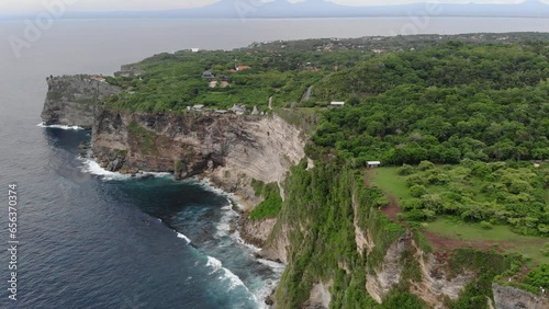 Bali, Indonasia. Aerial footage of transparent turquoise ocean and rocky cliffs, covered with tropical trees. photo