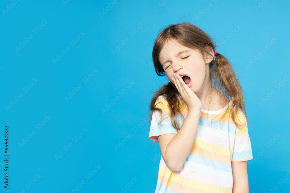 A little girl yawns on a blue background A little girl yawns on a blue background