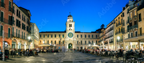 Fototapeta Naklejka Na Ścianę i Meble -  Padua, Italy - October 1, 2023: Piazza dei Signori or Piazza della Signoria in the evening. The square is dominated by the famous Clock Tower. People sitting at the tables in the bar or walking around