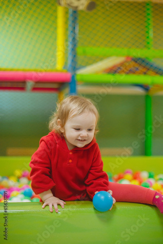 little girl playing in the children's playroom with colorful balls, toys in the entertainment center
