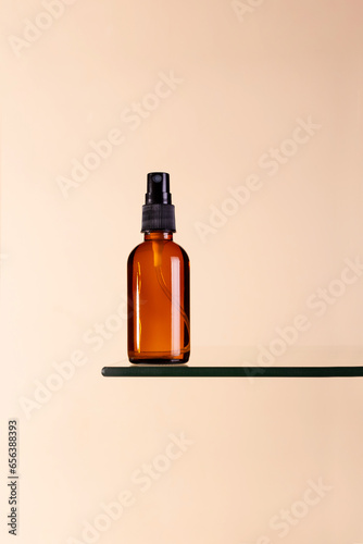Brown amber glass spray bottle with label mockup  on dais podium on beige background..