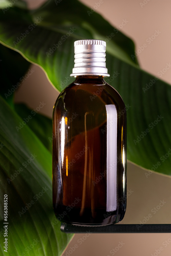 Bottle with cosmetic oil and green banana leaf on beige background. Concept anti aging, peptides, collagen and hyaluronic acid.