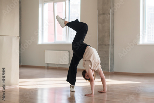 young girl doing acrobatic moves in the studio, jump in the air, dance and motion