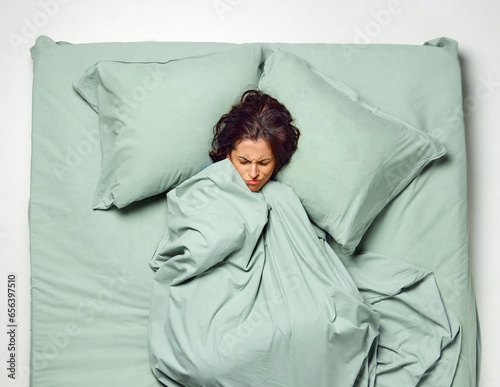 фотографія Young stressful, scared woman covered with blanket in dream lying in bad