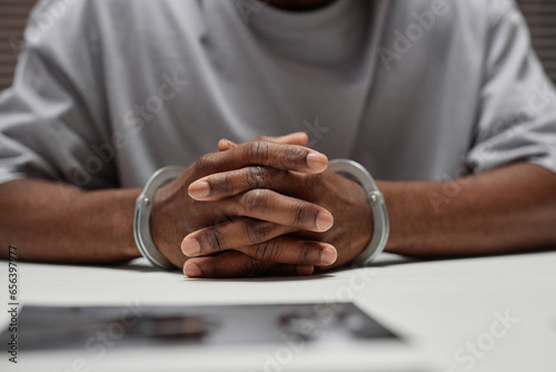 Foto Close up of anonymous black man wearing handcuffs sitting at table in police dep