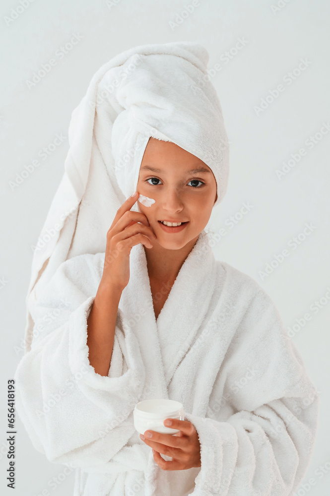 Putting cream on the face. Conception of beauty and self care. Young girl is in the studio Putting cream on the face. Conception of beauty and self care. Young girl is in the studio