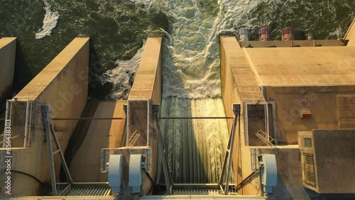 Close up top view of open sluice on dam wall. Rushing water creates turbulent water in river photo