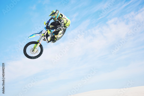 Motorbike, jump and person in the air with blue sky, mock up and stunt in sports with fearless person in danger with freedom. Motorcycle, jumping and athlete training for challenge or competition