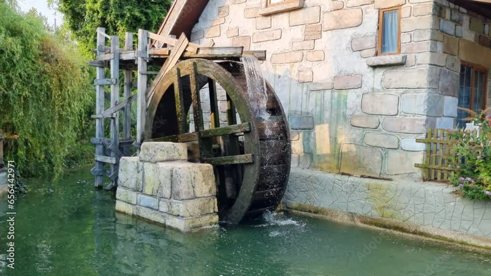 Large wooden wheel rotates under the pressure of water in an old watermill on the river. Large wooden wheel rotates under the pressure of water in an old watermill on the river.