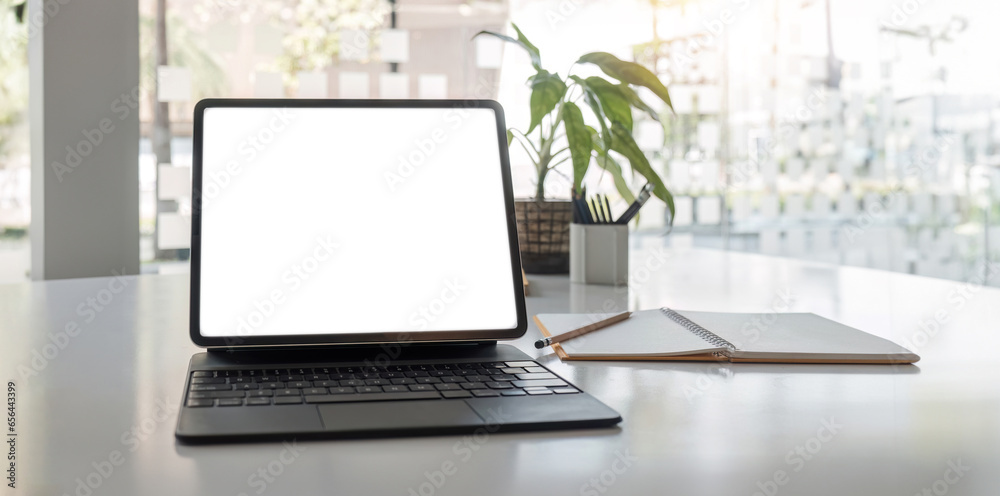laptop white screen mockup, painting tools, notebook, and decor on a table in a modern contemporary living room. close-up workspace. laptop white screen mockup, painting tools, notebook, and decor on a table in a modern contemporary living room. close-up workspace.