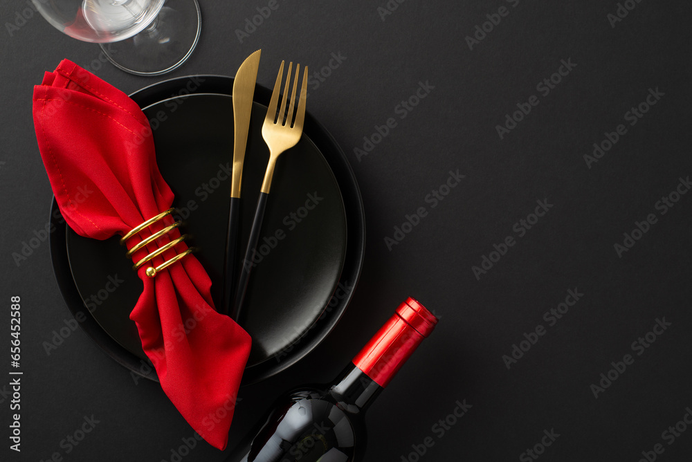 Black Friday luxury dining: Top view of impeccably arranged table, showcasing exquisite dinnerware, cutlery, red napkin with ring, wine bottle, glass on a black base. Ideal for your promotional needs - obrazy, fototapety, plakaty 