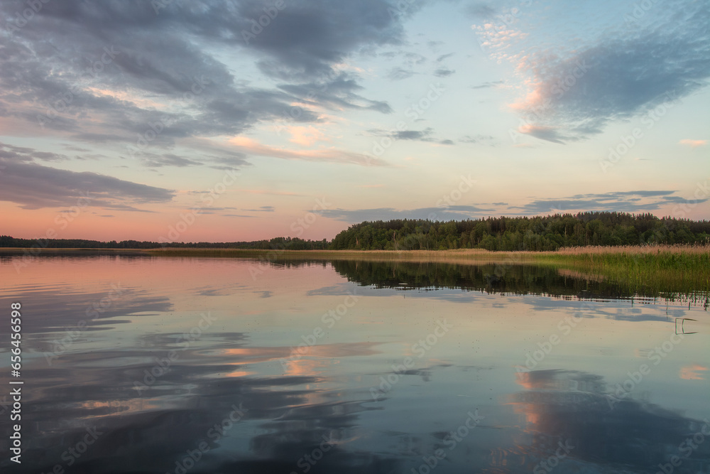 Scenery of nature of Braslav lakes. Beautiful sunset on Snudy lake, the sky is overcast with small clouds. The sky is reflected from the surface of the lake water.