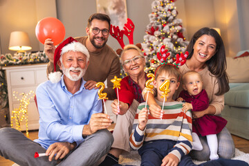 Family celebrating New Year holding little balloons shaped as numbers 2024