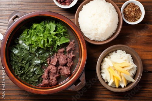 overhead view of feijoada, rice, and greens on a wooden table