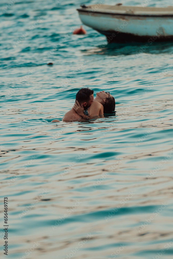 A romantic young couple sharing a passionate kiss amidst the serene beauty of the ocean at sunset.
