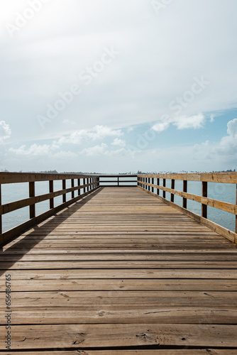 perspective of a wooden bridge in a coast with a cloudy sky from puerto rico 