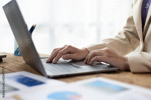 Businesswoman analyzing business reports and financial data on laptop.