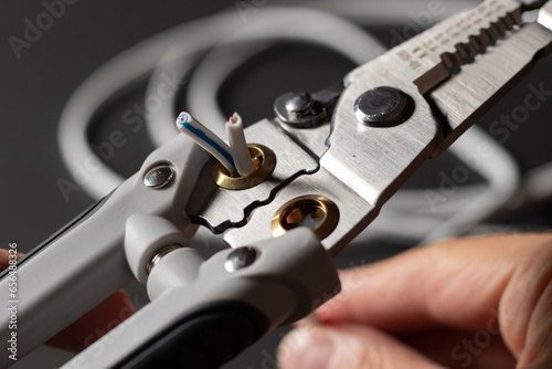 Photos An electrician wearing gray work gloves is stripping electrical wires with a stripper