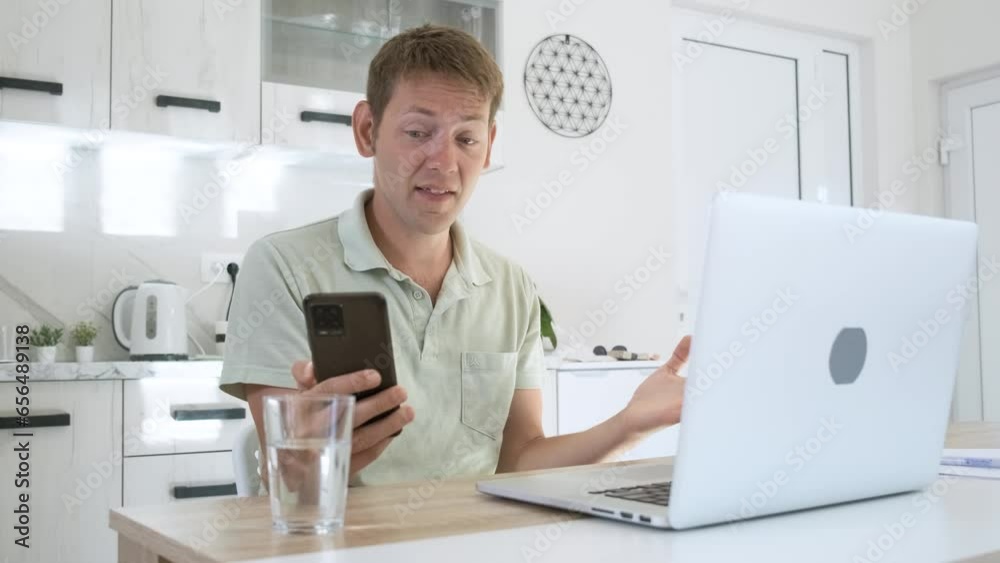 Angry male yelling and screaming on mobile phone while working on laptop online at home. Annoyed man freelancer shouting into the phone gesturing, describing a problem to be solved Angry male yelling and screaming on mobile phone while working on laptop online at home. Annoyed man freelancer shouting into the phone gesturing, describing a problem to be solved
