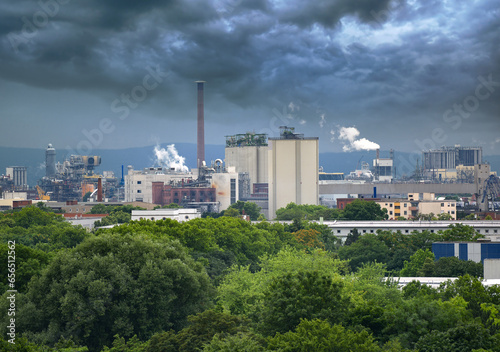 Aerial view of large factory with chimneys emitting smoke into the environment.