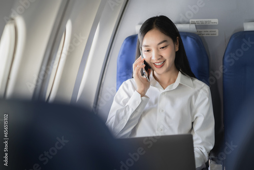 Waist up image of a fun business woman in an airline working on his computer while talking on a cell phone.