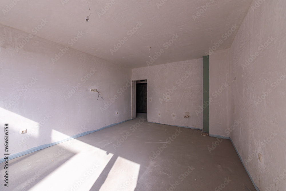 Obraz premium New empty room under construction. Plaster walls. New home. Concrete walls. Interior renovation.