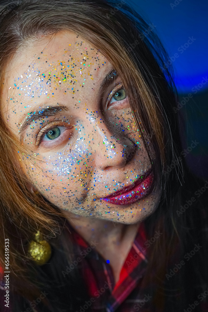 Shiny silver makeup on a woman's face. Beautiful young model girl with shine on the skin. A close-up of the girl's face glistens with glitter and shimmers in the light. New Year, Christmas, birthday. Shiny silver makeup on a woman's face. Beautiful young model girl with shine on the skin. A close-up of the girl's face glistens with glitter and shimmers in the light. New Year, Christmas, birthday.