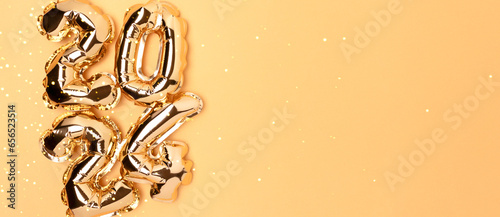 Banner with 2024 foil balloons on a golden background with copy space. New Year composition.