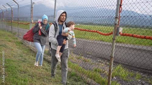 migrant family walk along fence border relocation problem
