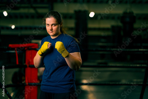 Bild auf Leinwand portrait focused Boxer girl in yellow boxing bandages standing in a boxing stanc