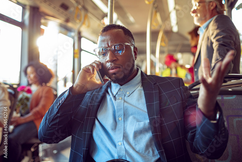 Young businessman talking on the smartphone while commuting to work on a bus photo