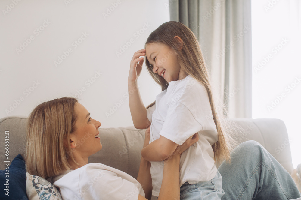 Mother and daughter having fun spending leisure time together at home playing and cuddling. Mother and daughter having fun spending leisure time together at home playing and cuddling.