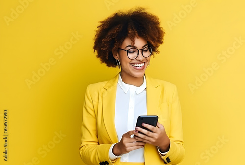 Colorful studio portrait of a young african-american woman with glasses using a smartphone, yellow dominant color. Copy space