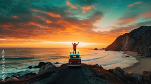 A man stands on the roof of a minivan on the beach