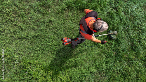 High angle view of modern gardener mows the grass with lawn mower.