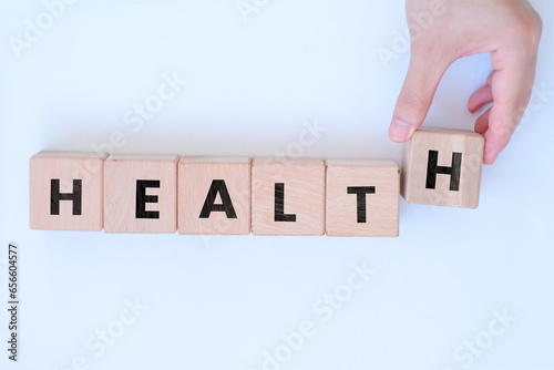 Fototapeta Naklejka Na Ścianę i Meble -  Man hand ordering Health text on block cubes, medical or disease idea, wooden block cubes with Health word on it, wood blocks on white background, banner concept