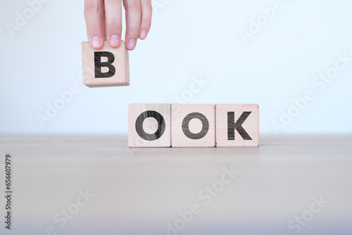 Man hand ordering Book letters on block cubes, reading or education concept, wooden block cubes with Book word on it, wood blocks on white background, banner idea