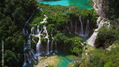 People hiking on narrow path in Plitvice Lakes National Park Croatia. Mountain landscape with streams of water and waterfalls.