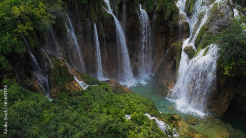 Waterfalls in green mountain forest landscape with streams of water. Cascades flow among lush greenery in spring or summer.