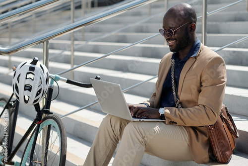 Slika na platnu Young African American male solopreneur or freelancer typing on laptop keyboard