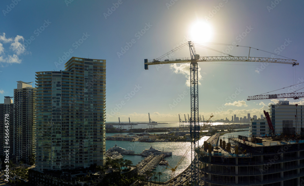 New construction site of developing residense in american urban area. Industrial tower lifting cranes in Miami, Florida. Concept of housing growth in the USA New construction site of developing residense in american urban area. Industrial tower lifting cranes in Miami, Florida. Concept of housing growth in the USA