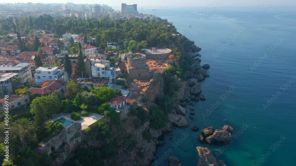 Enjoy a breathtaking view of Hidirlik Tower, an iconic symbol of Antalya's historical center, in this mesmerizing aerial stock video. The tower, with its ancient charm and stunning location