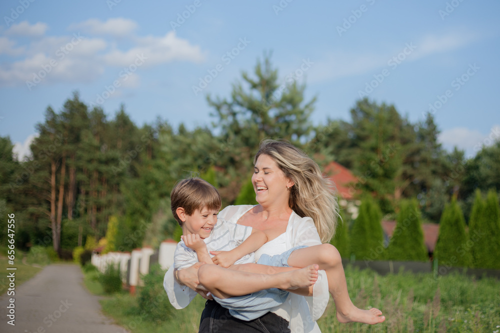 Single parents. Mom and son have fun and indulge during walk on warm summer day on rural road .