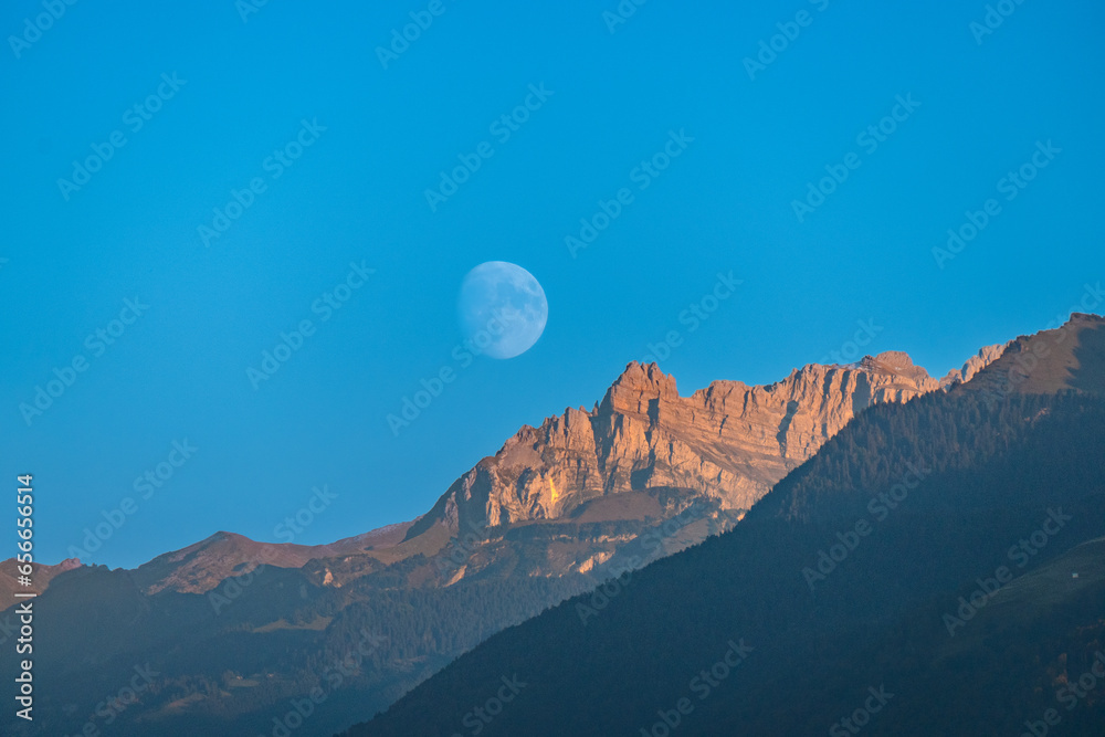 Beautiful waning moon over the wägital mountains, canton Schwyz, Switzerland. View from the Seedam on the shores of the upper Zurich Lake.