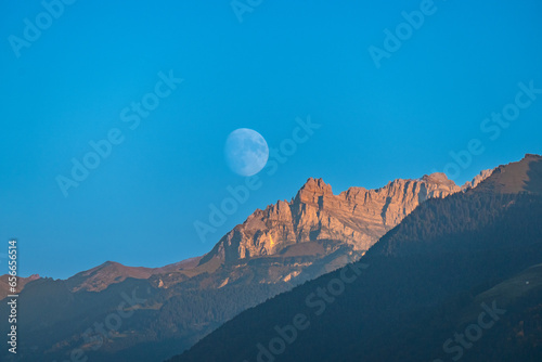 Fotografie Beautiful waning moon over the wägital mountains, canton Schwyz, Switzerland