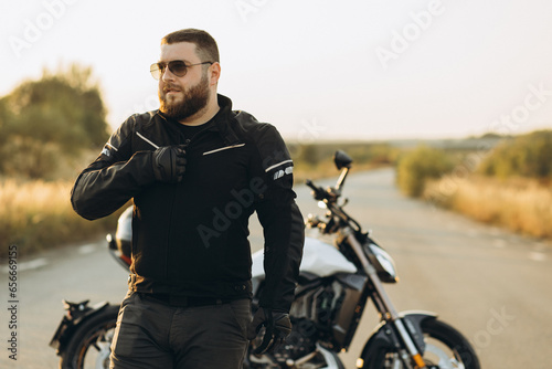 Man biker standing by his bike holding his helmet